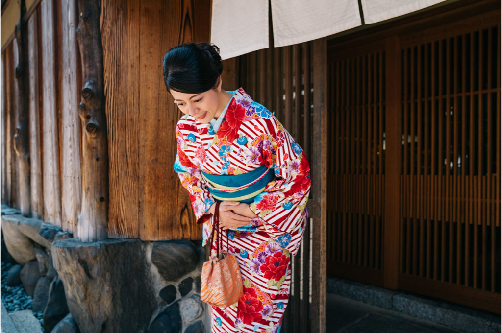 Dame japonaise s'inclinant devant sa maison avec un beau kimono