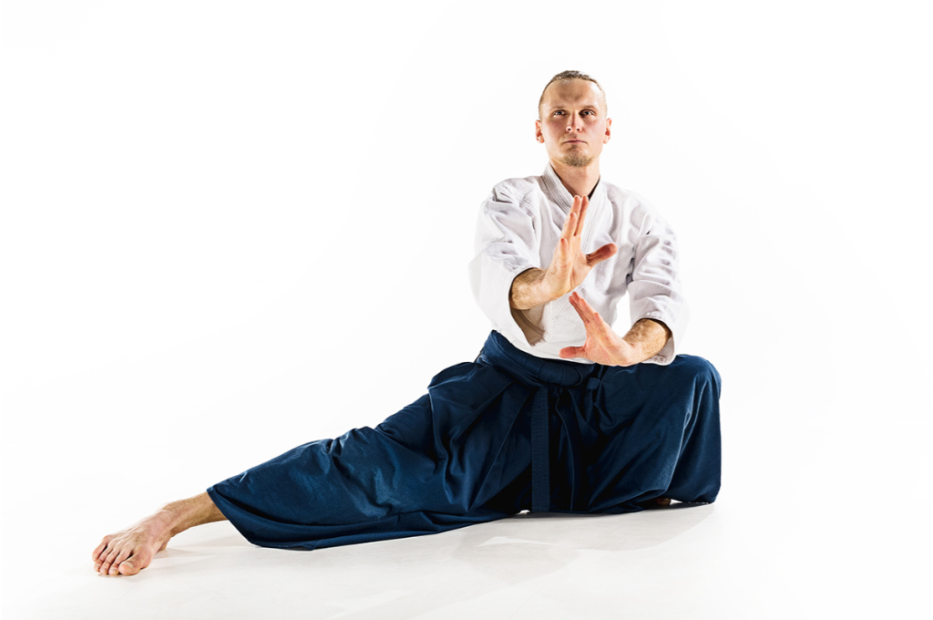 maitre d'aïkido faisant une pose d'aïkido avec une jambe sur le côté et les mains devant lui