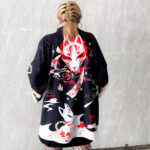 Une femme de dos montre son kimono de couleur noir avec un motif imprimé de renard en rouge et blanc