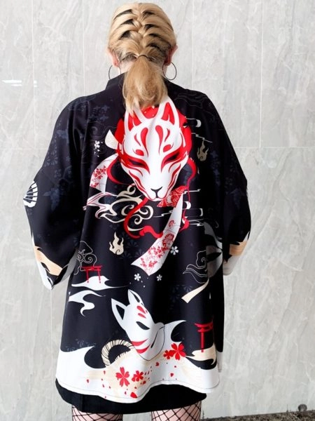 Une femme de dos montre son kimono de couleur noir avec un motif imprimé de renard en rouge et blanc