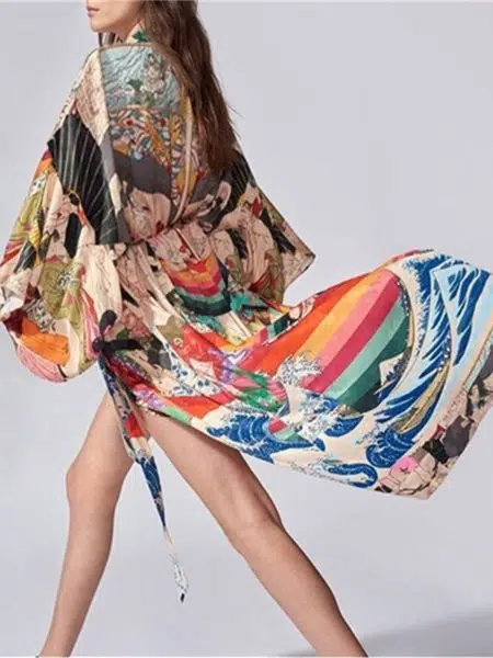 Femme en train de marcher, ellle porte un kimono de plage dont la jupe flotte au vent, il est multicolore