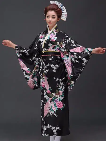 Une femme porte un kimono noir avec des motifs japonais à manches larges, ses cheveux sont coiffés en chignons traditionnels, ses bras son ouverts de part et d'autre