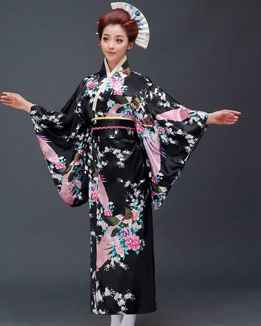 Une femme porte un kimono noir avec des motifs japonais à manches larges, ses cheveux sont coiffés en chignons traditionnels, ses bras son ouverts de part et d'autre