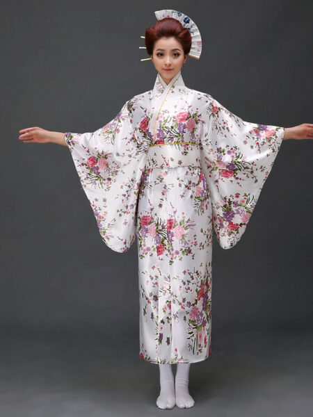 Une femme porte un kimono blanc avec des motifs japonais à manches larges, ses cheveux sont coiffés en chignons traditionnels, ses bras son ouverts de part et d'autre