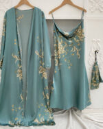 Ensemble nuisette et kimono vert à imprimé floral suspendus à des cintres devant un mur blanc avec des moulures et sur un drap blanc