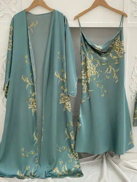 Ensemble nuisette et kimono vert à imprimé floral suspendus à des cintres devant un mur blanc avec des moulures et sur un drap blanc
