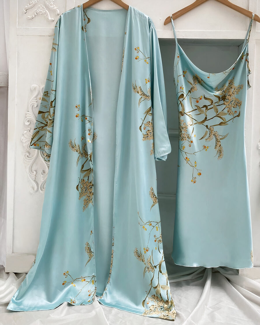 Ensemble nuisette et kimono bleu à imprimé floral suspendus à des cintres devant un mur blanc avec des moulures et sur un drap blanc