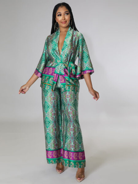 Ensemble pantalon kimono de couleur vert avec des motifs floraux et géométriques de couleurs violets et verts, porté par une femme devant un mur gris