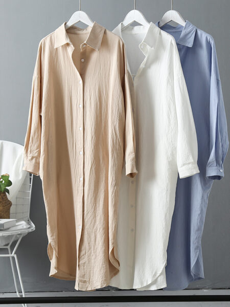 Tunique de plage de couleur beige, blanche et bleue suspendues à des cintres blancs à côté d'une chaise en fer blanc