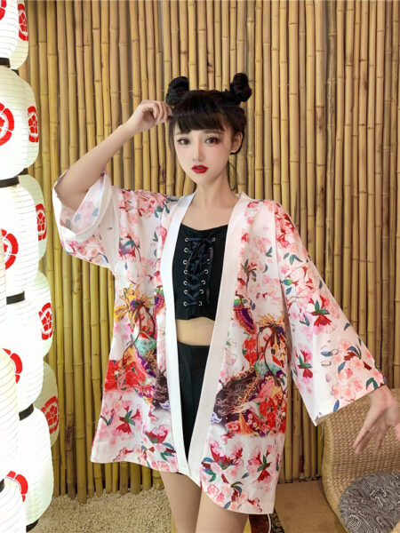 Une femme debout dans une chambre portant un kimono de style japonais de couleur blanche et rose avec des motifs fleuris colorés.