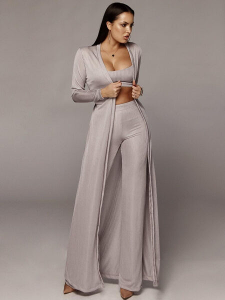 Une femme brune vêtue d'un kimono trois pièces de couleur grise comprenant un pantalon moulant, un débardeur et une veste longue légère ouverte sur le devant, le tout dans le même coloris.