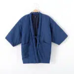 Un haut de kimono pour femme en jean délavé de couleur bleu. il est sur un ceintre. sa fermeture est faite par une ceinture de meme coloris.
