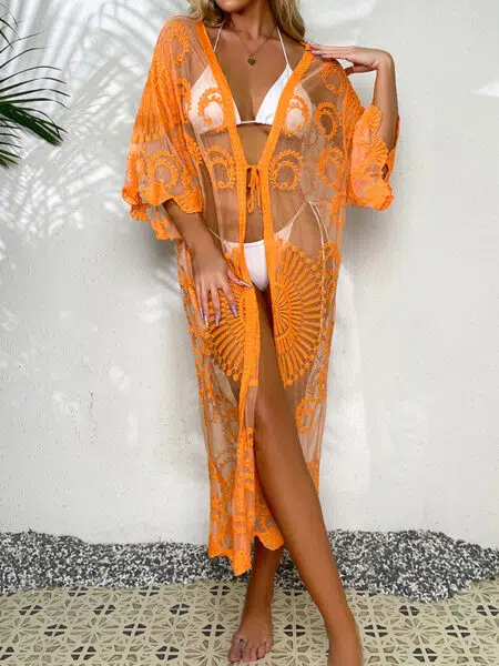 jeune femme appuyée sur un mur blanc de dos, porte un bikini blanc et un kimono en dentelle orange pour la plage