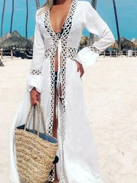 sur un plage une femme porte un kimono en dentelle blanc avec motifs découpés, et un sac en osier et un chapeau blanc