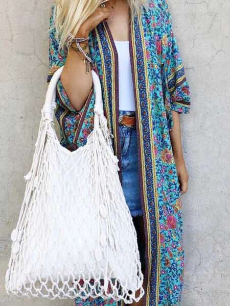 Kimono japonais à imprimé floral turquoise, porté par une femme debout avec un sac à main blanc