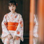 Kimono japonais traditionnel blanc à motifs floraux colorés, porté par une femme debout