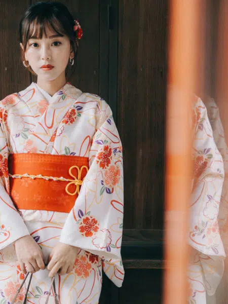 Kimono japonais traditionnel blanc à motifs floraux colorés, porté par une femme debout