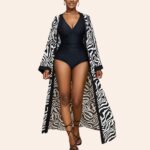 Kimono long femme noir et blanc fluide porté par une jeune femme en maillot de bain noir, sur fond beige