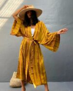 Femme en maillot de bain portant un kimono de plage imprimé tie and dye jaune sur fond gris