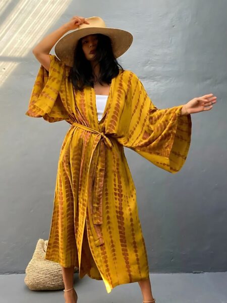 Femme en maillot de bain portant un kimono de plage imprimé tie and dye jaune sur fond gris