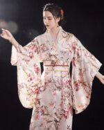 Femme portant un kimono japonais traditionnel blanc et rose à motif floral sur fond noir