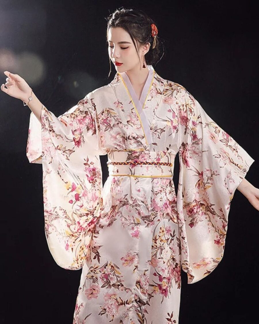 Femme portant un kimono japonais traditionnel blanc et rose à motif floral sur fond noir