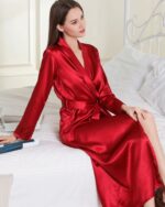 Femme portant un peignoir kimono long en satin rouge sur son lit