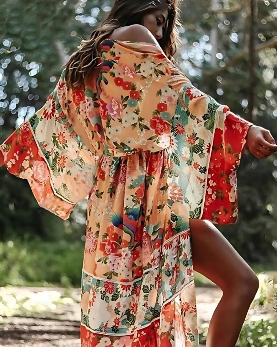 Femme portant un kimono long fleuri au style bohème de couleur orange dans un jardin